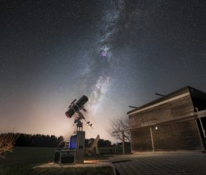 Eine magische Szenerie!  Hoch am Himmel prangt auff&auml;llig das majest&auml;tische Band der Milchstra&szlig;e. Mit dem Teleskop im Vordergrund wird ein kleiner Teil dieser kosmischen Pracht eingefangen und so f&uuml;r jedermann zug&auml;nglich! 