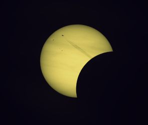 Wie aus einer surrealen Welt! Der D&uuml;senjet schie&szlig;t wie aus dem Nichts aus der abgedunkelten Mondscheibe heraus geradewegs der angeknabberten hellen Sonne entgegen. Partielle Sonnenfinsternis 12. August 2026
